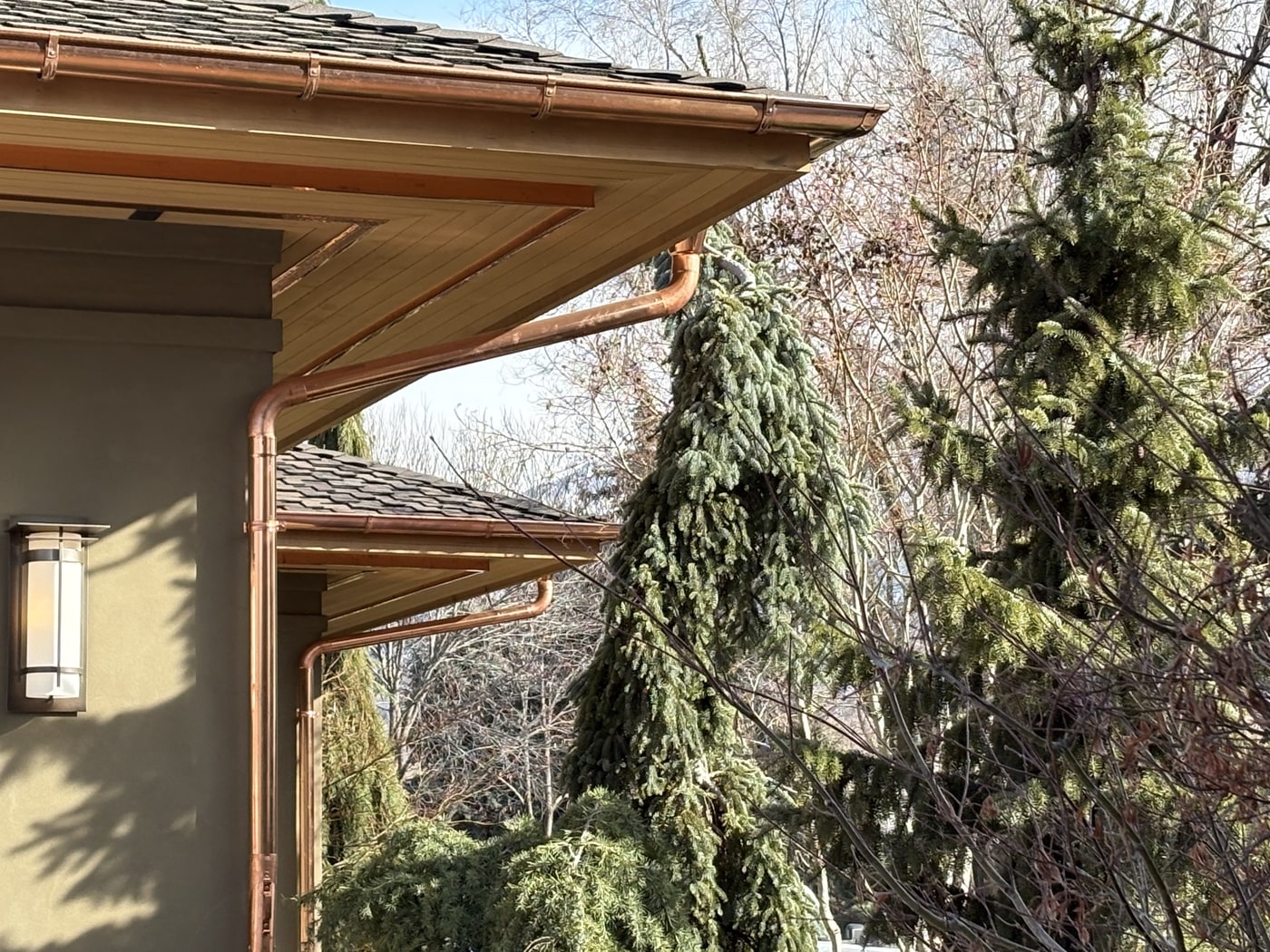 Copper half-round gutter at a roofline corner with wood fascia on a Northern Utah home.