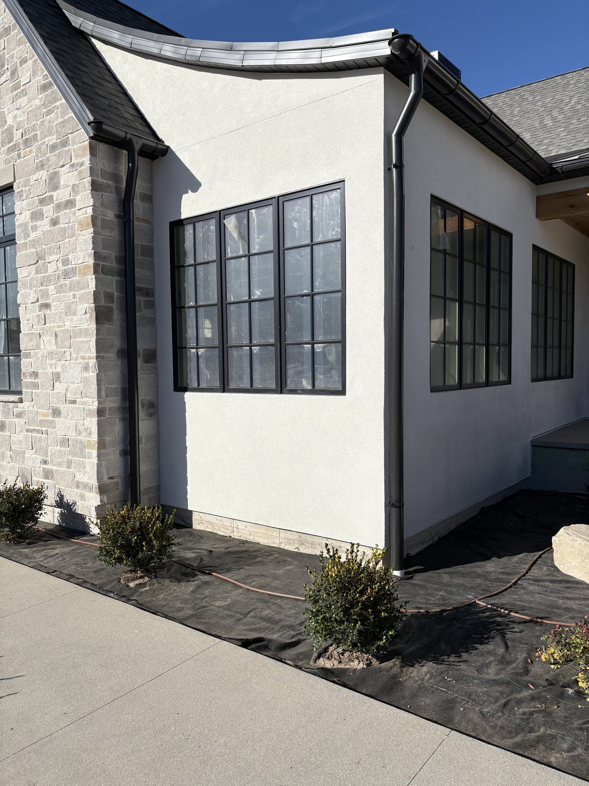 Charcoal K-style gutter system and downspout on a white stucco luxury home.