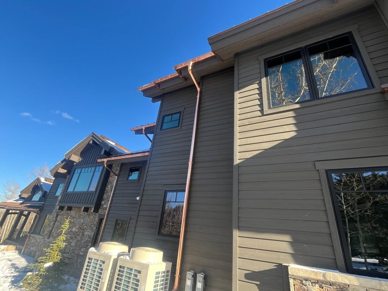 Copper half-round gutter and downspout on a Park City custom mountain home, blue sky.