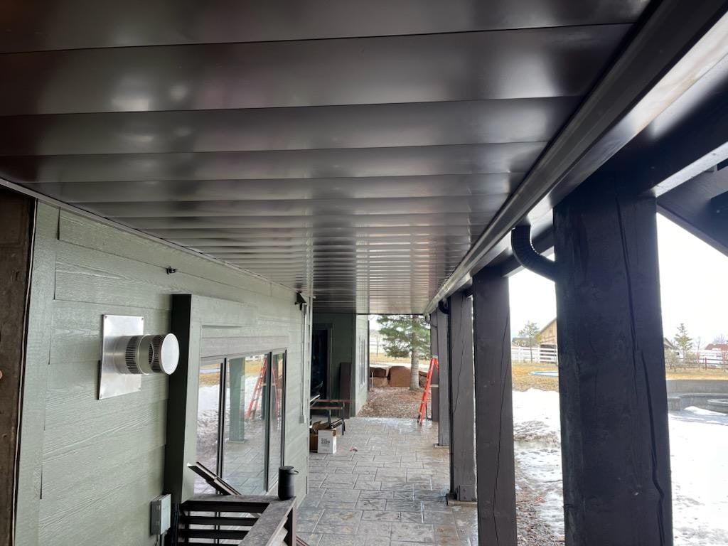 Dark metal panel ceiling on a covered patio with integrated under-deck drainage system.